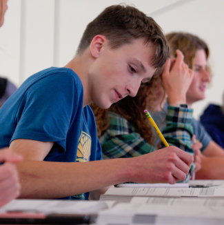male student writing with a pencil